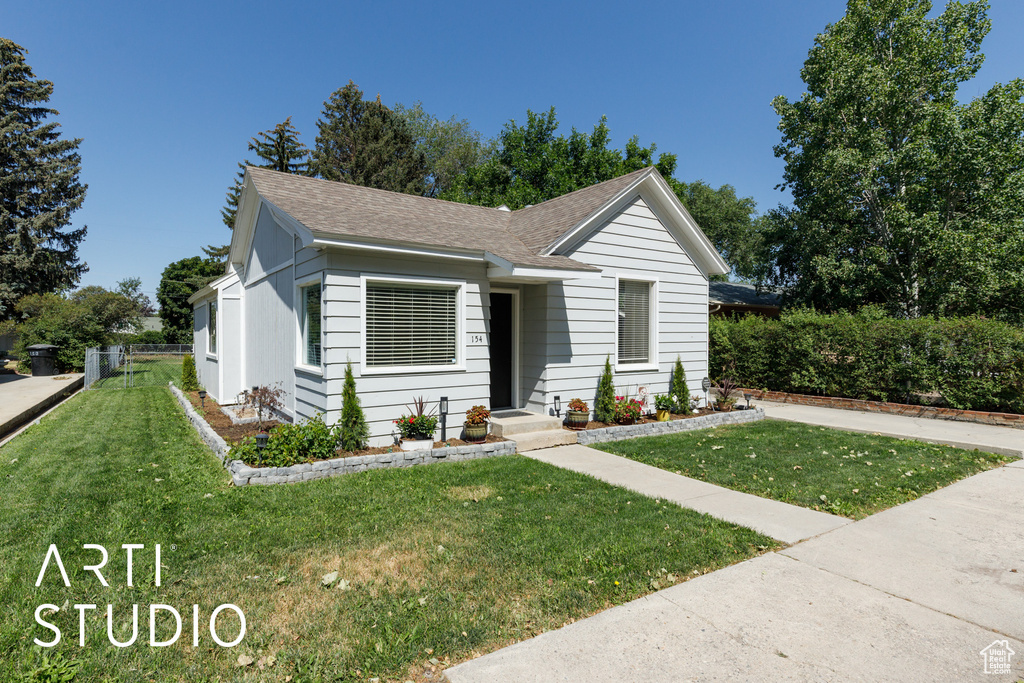 Ranch-style house featuring roof with shingles and a front yard