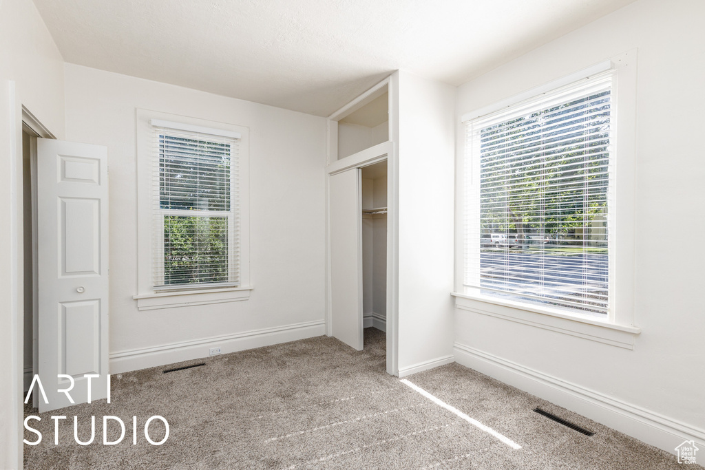 Unfurnished bedroom with carpet flooring and multiple windows