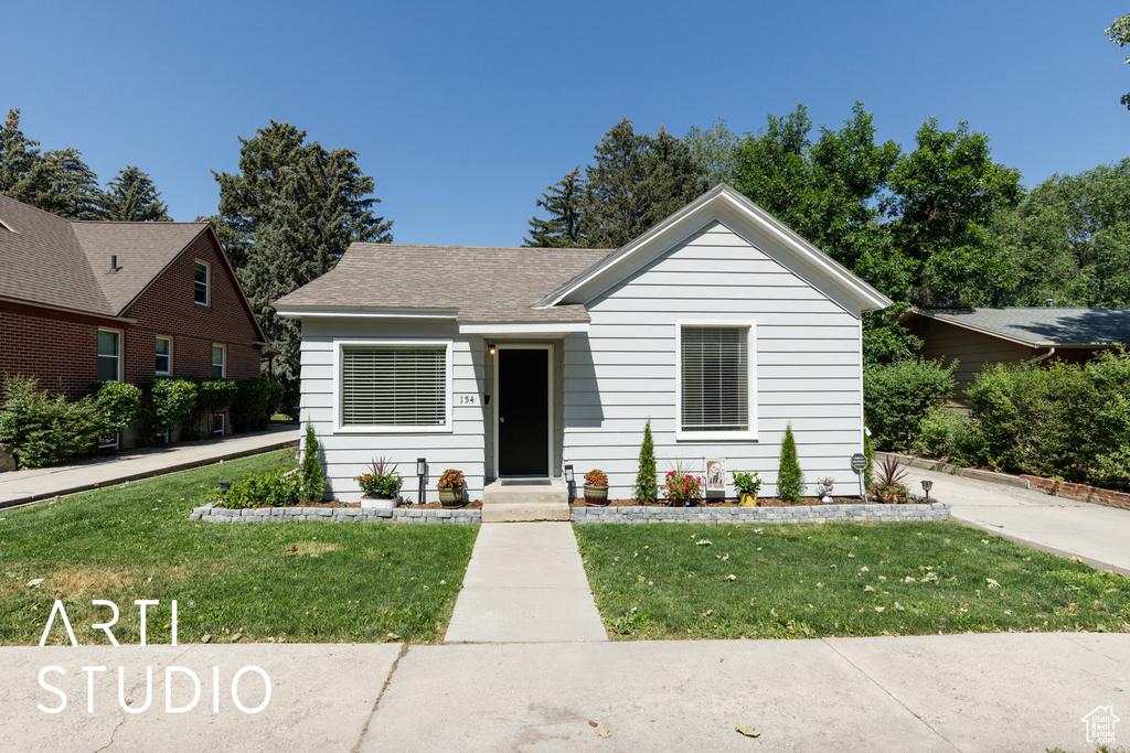 View of front of home featuring a front lawn and roof with shingles