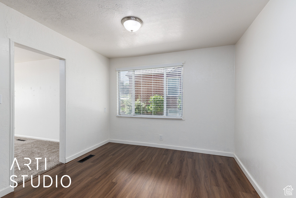 Spare room with dark wood-style flooring and baseboards