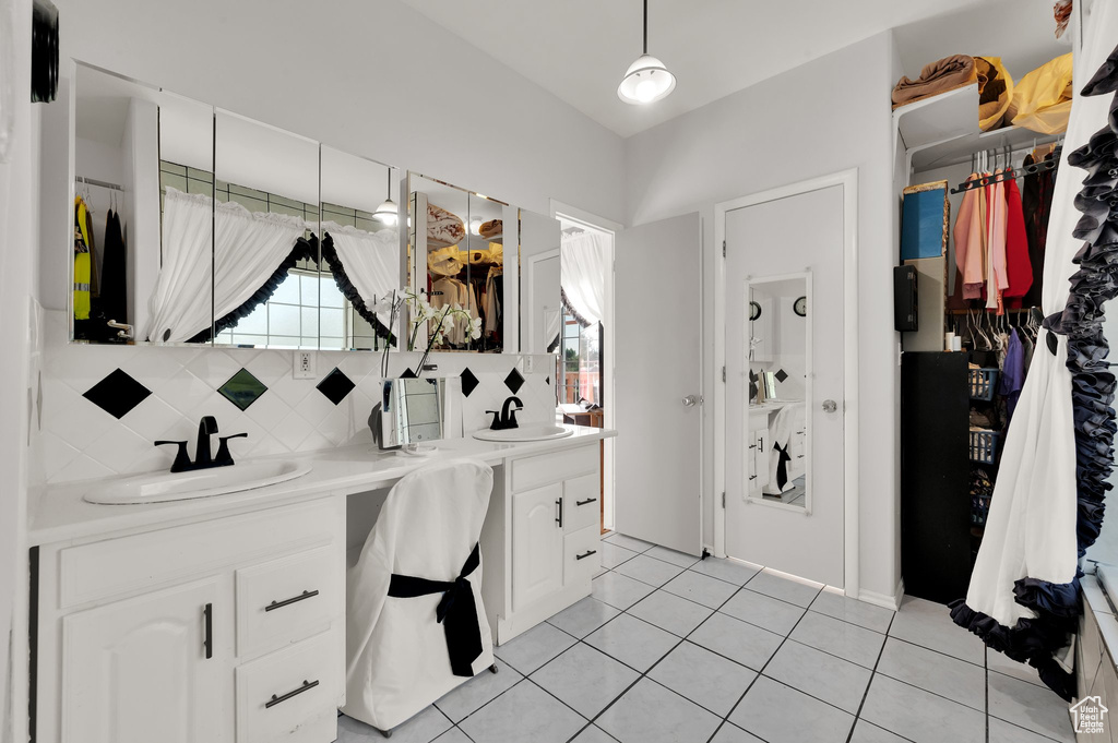 Full bathroom with double vanity, tile patterned flooring, tasteful backsplash, and a walk in closet