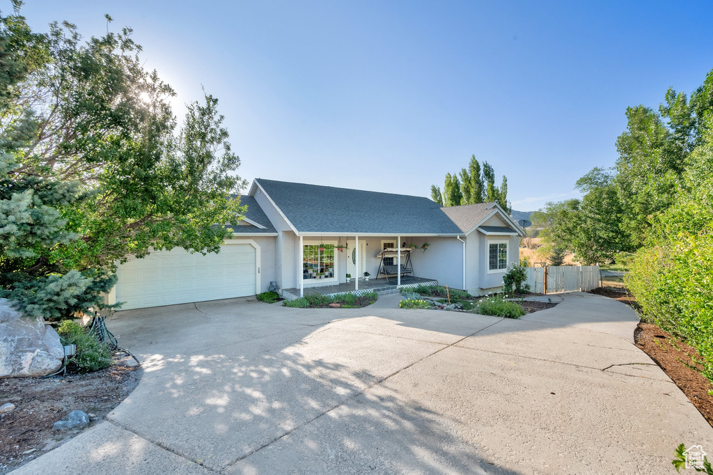 View of front of house with a porch, driveway, a garage, and stucco siding