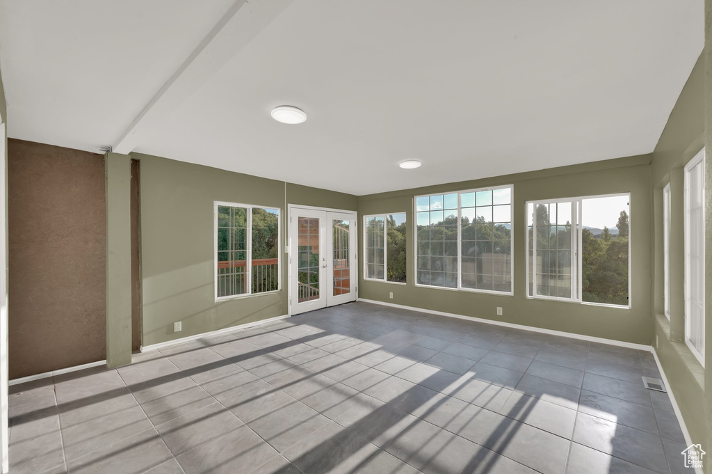 Unfurnished sunroom with tile patterned flooring and french doors