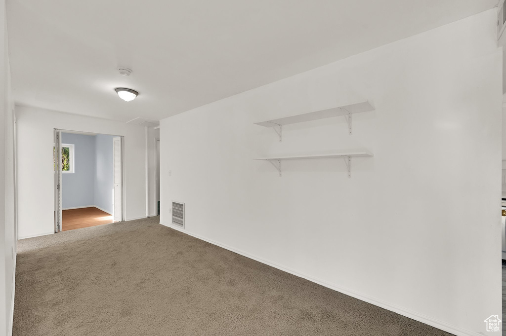 Carpeted empty room featuring a smoke detector