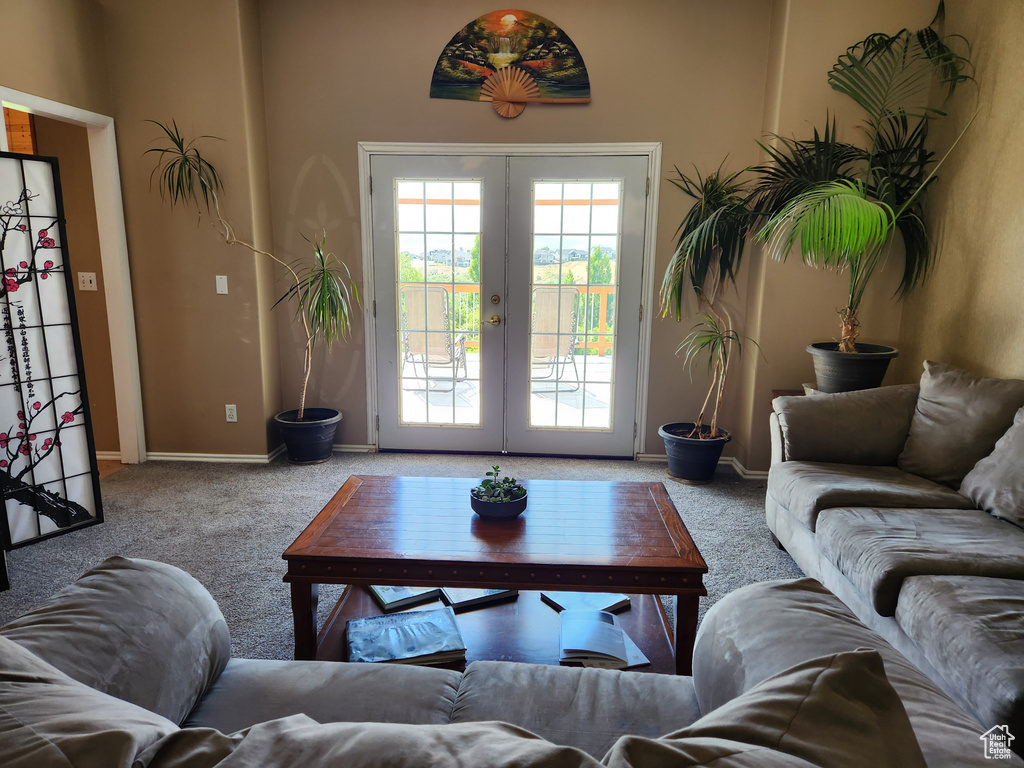 Carpeted living area featuring french doors and baseboards