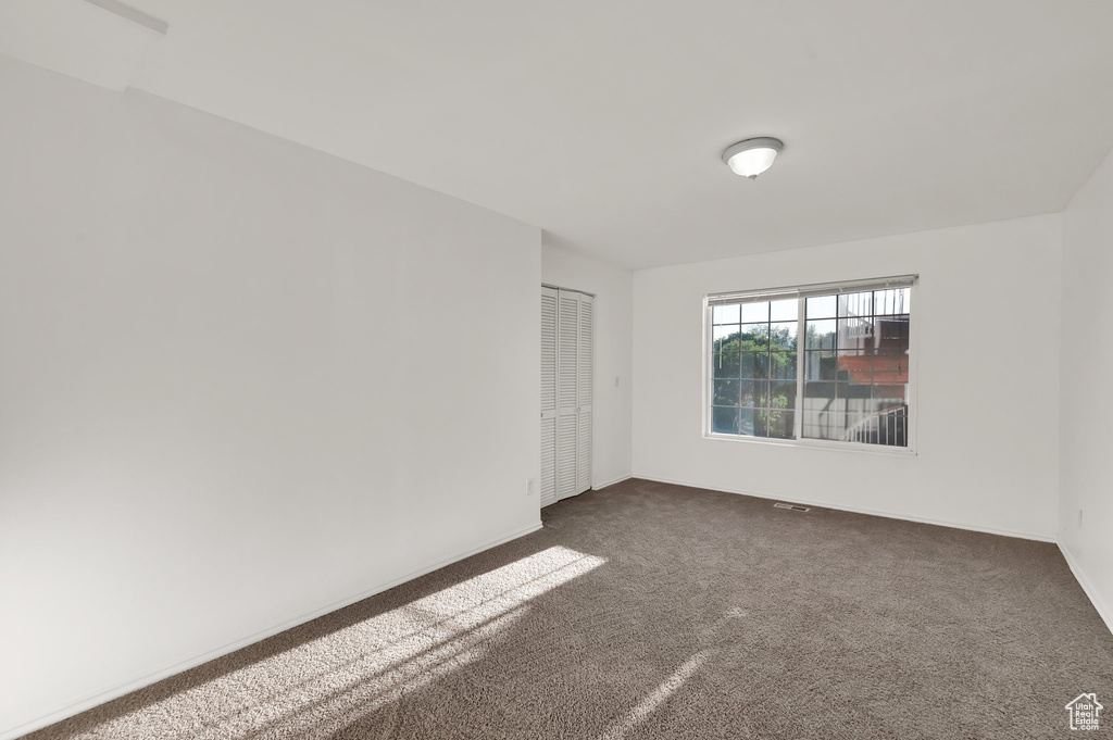 Unfurnished room featuring dark carpet and baseboards