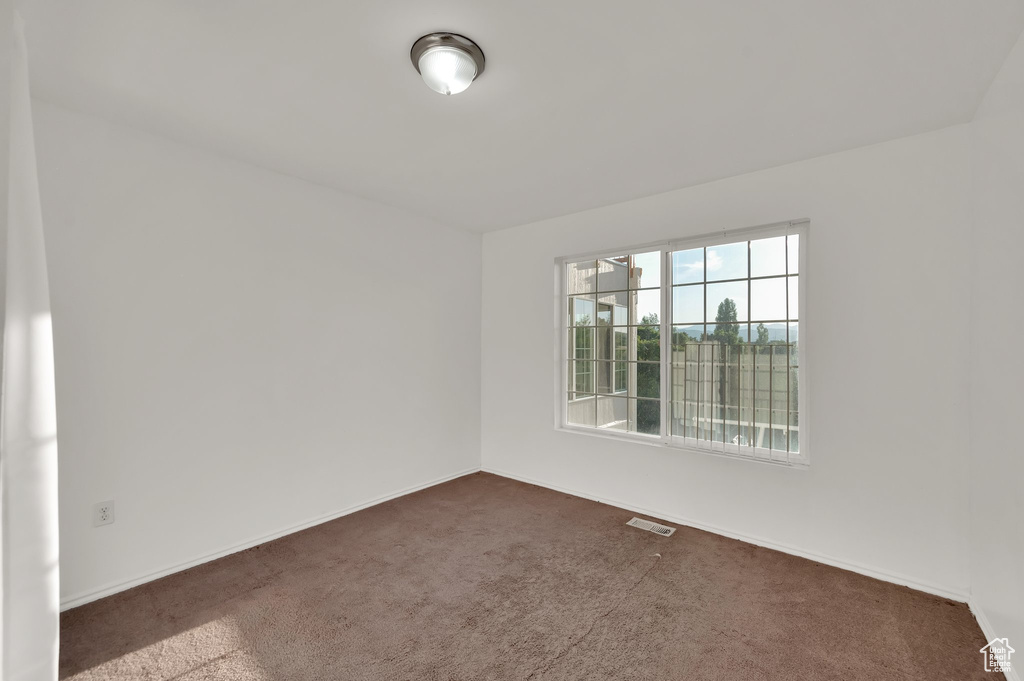 Unfurnished room featuring dark carpet and baseboards