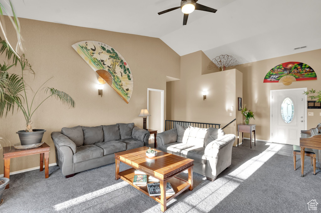 Carpeted living area featuring a ceiling fan and high vaulted ceiling
