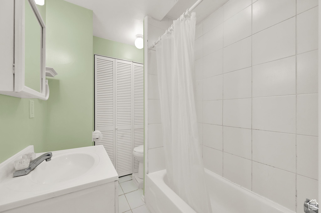 Bathroom featuring shower / bathtub combination with curtain, vanity, tile patterned flooring, and a closet