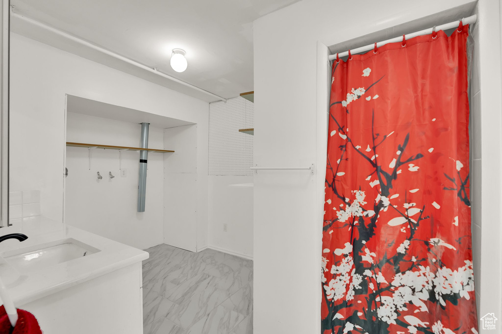 Bathroom with marble look tile flooring, vanity, and a shower with shower curtain