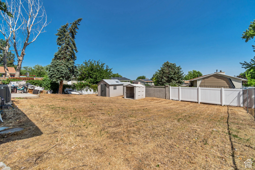 Fenced backyard with a storage unit and a patio area