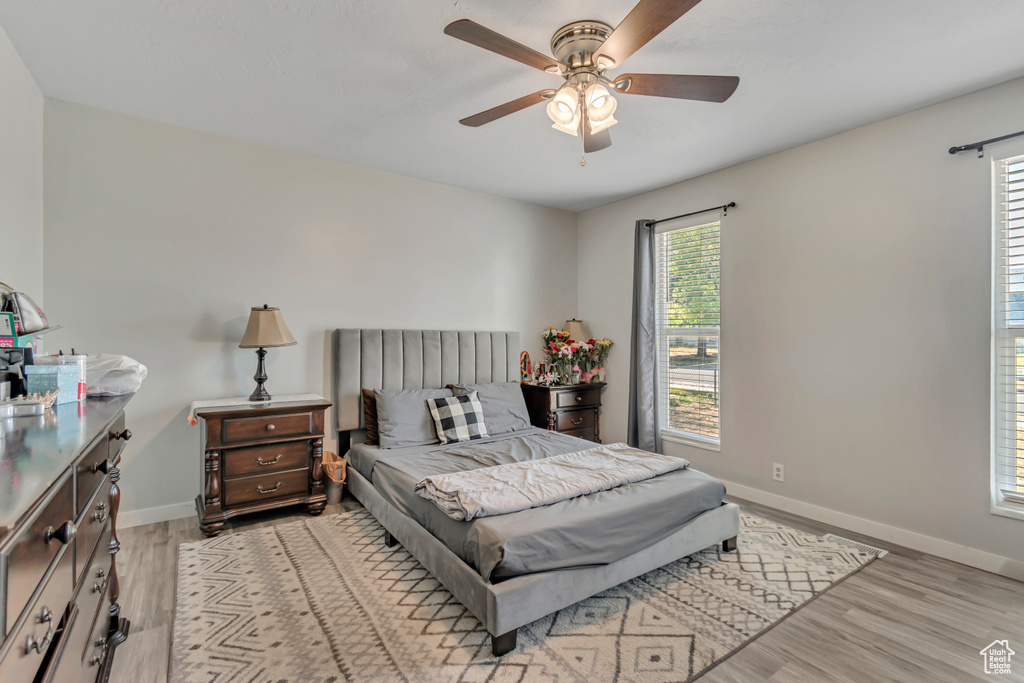 Bedroom with multiple windows, light wood-style floors, and ceiling fan
