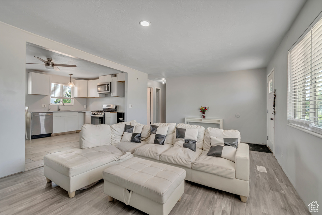 Living room with light wood-style flooring, a ceiling fan, and recessed lighting