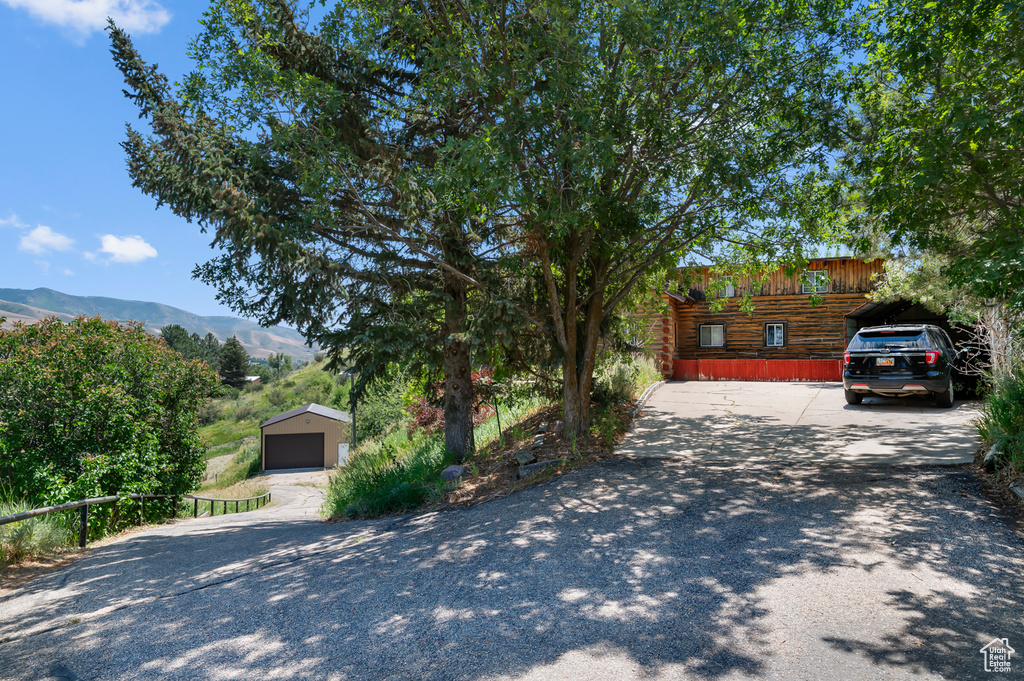View of front of house with a detached garage, an outbuilding, a mountain view, and log siding