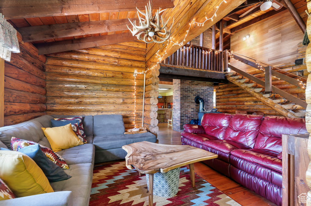 Living area with wooden ceiling, log walls, wood-type flooring, and a wood stove