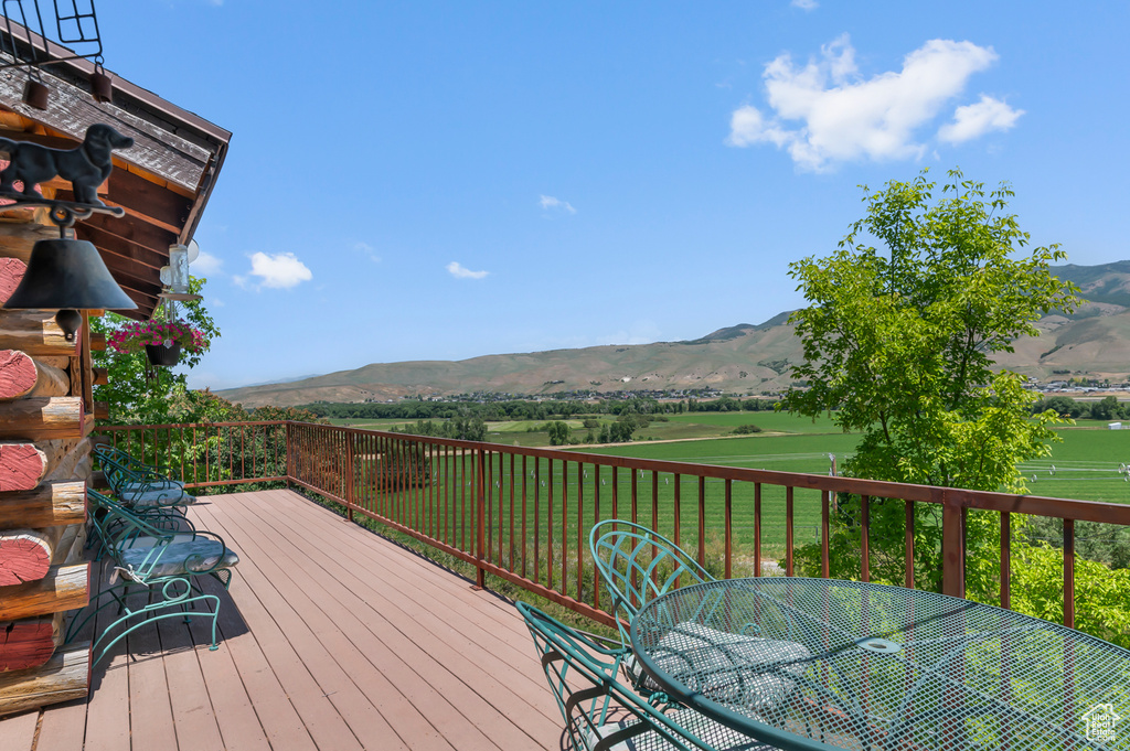 Wooden terrace with a mountain view, outdoor dining area, and a lawn