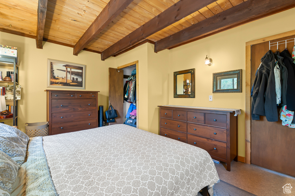 Bedroom featuring a wood ceiling with exposed beams, a spacious closet, carpet flooring, and a closet
