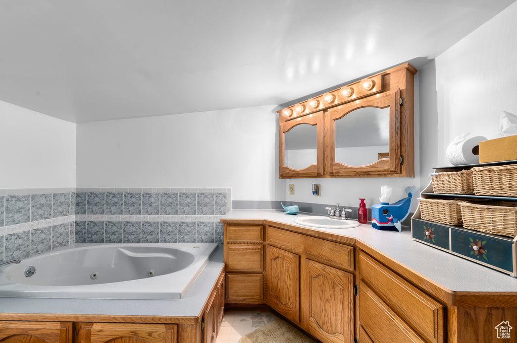 Full bathroom featuring vanity, a tub with jets, and tile patterned floors