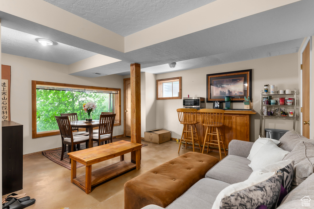 Living area with a bar, a textured ceiling, and finished concrete floors