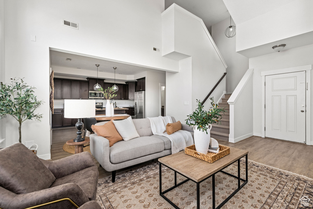 Living room featuring light wood finished floors, a high ceiling, and stairway