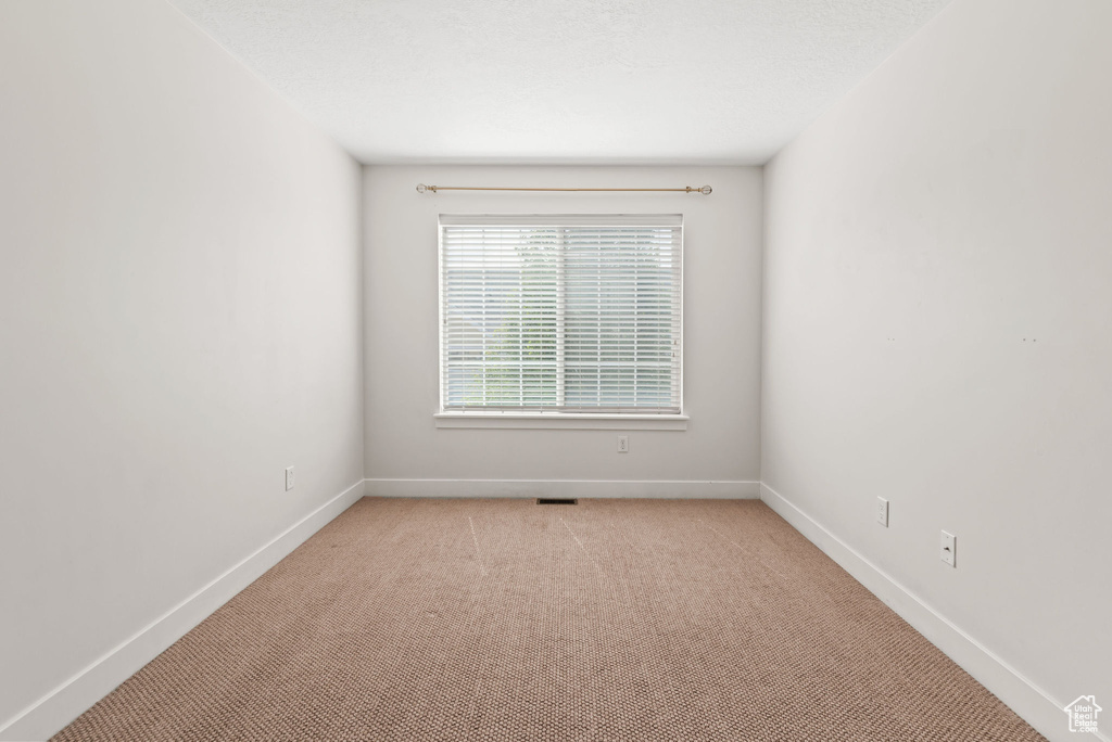 Unfurnished room featuring light carpet and baseboards