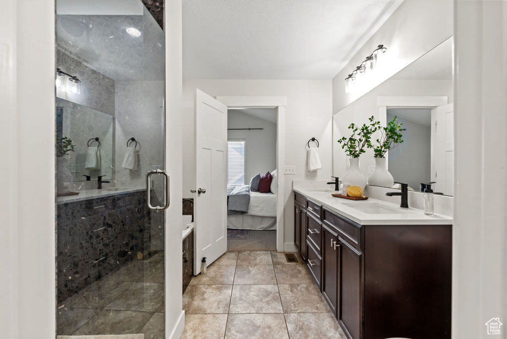 Bathroom with double vanity, a stall shower, connected bathroom, and tile patterned floors
