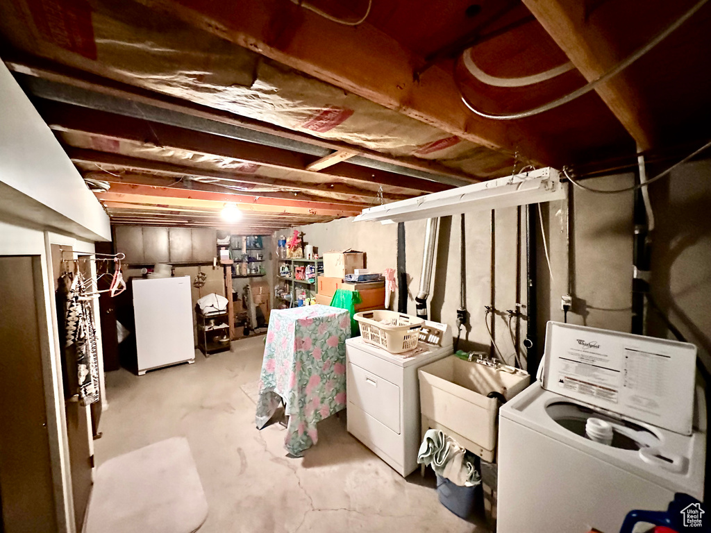 Unfinished basement featuring washing machine and dryer and white refrigerator