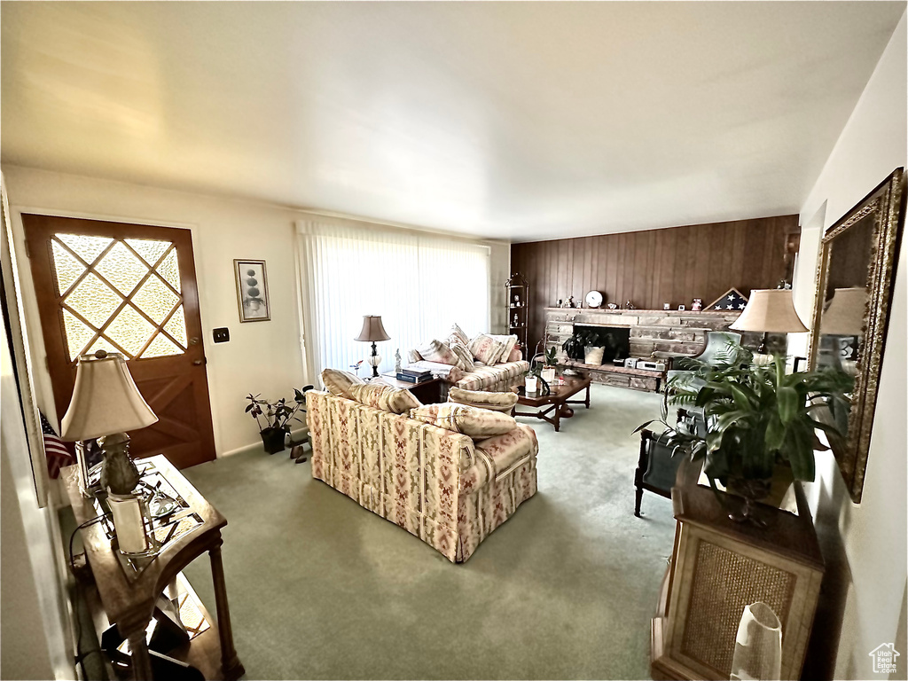 Carpeted living room featuring healthy amount of natural light, wood walls, and a fireplace