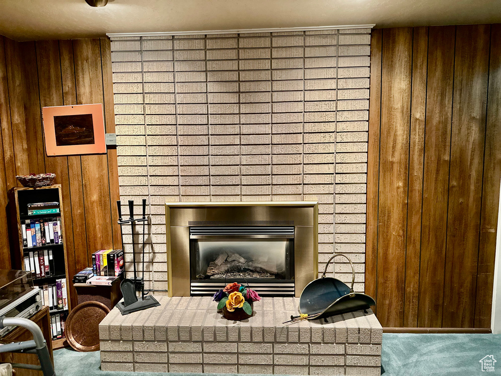 Detailed view of carpet, a fireplace, and wooden walls