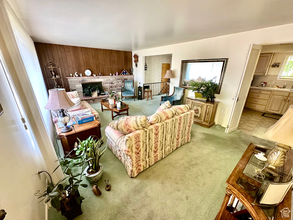 Living area with light colored carpet, wooden walls, and a fireplace