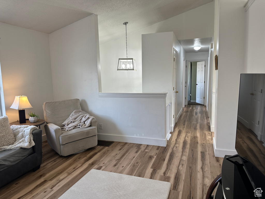 Living area featuring wood finished floors, lofted ceiling, and a chandelier