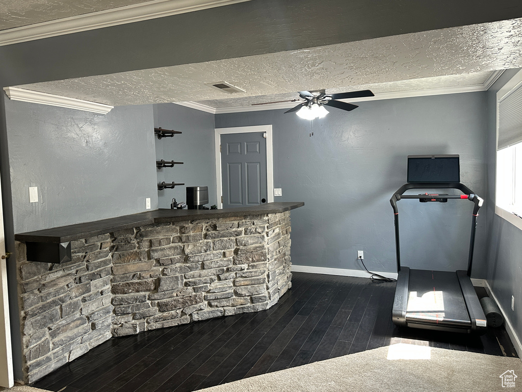 Indoor bar with a textured ceiling, hardwood / wood-style flooring, a ceiling fan, and ornamental molding