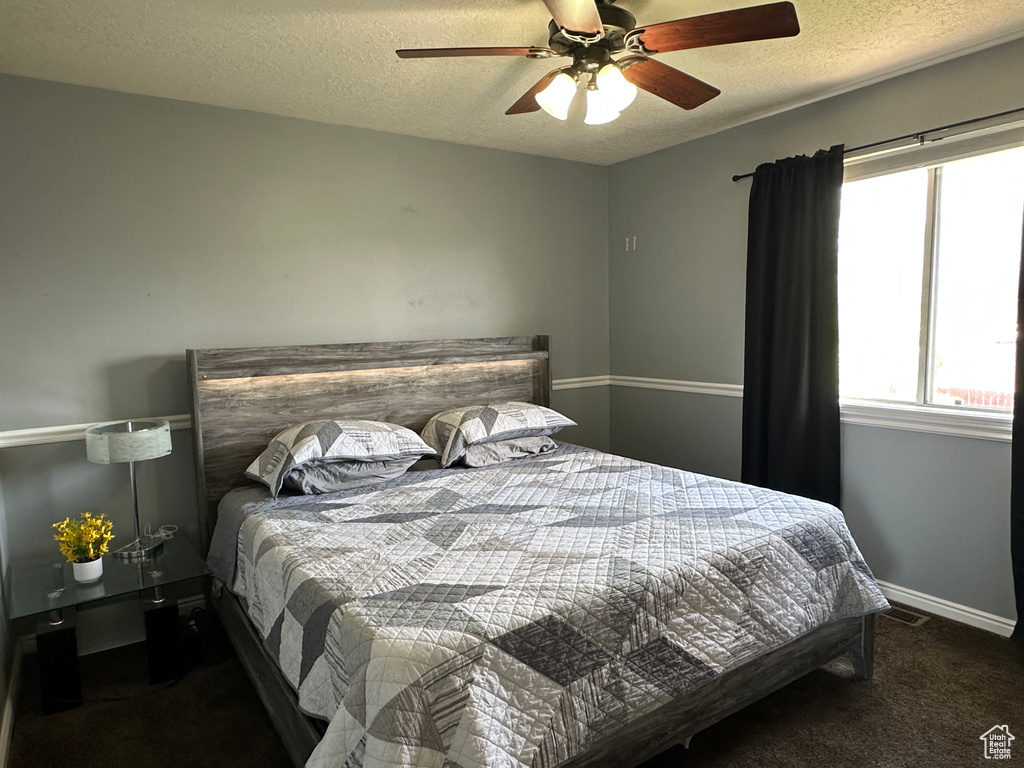 Carpeted bedroom with a textured ceiling and ceiling fan