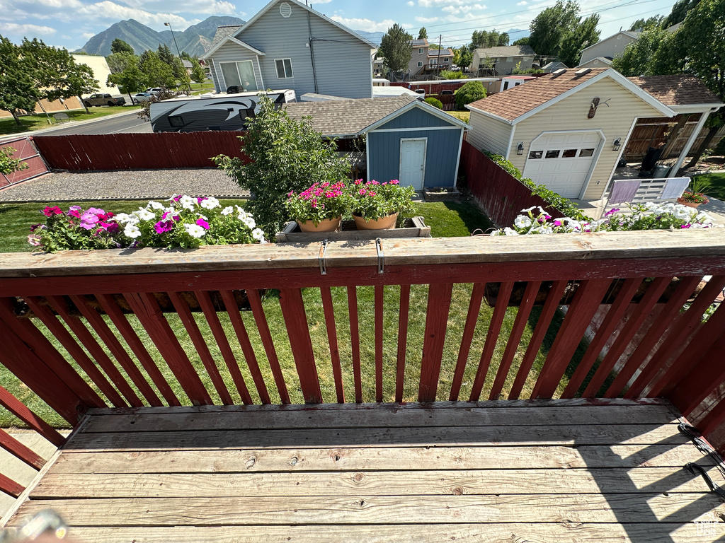 Wooden deck with a storage shed, a detached garage, a residential view, and a mountain view