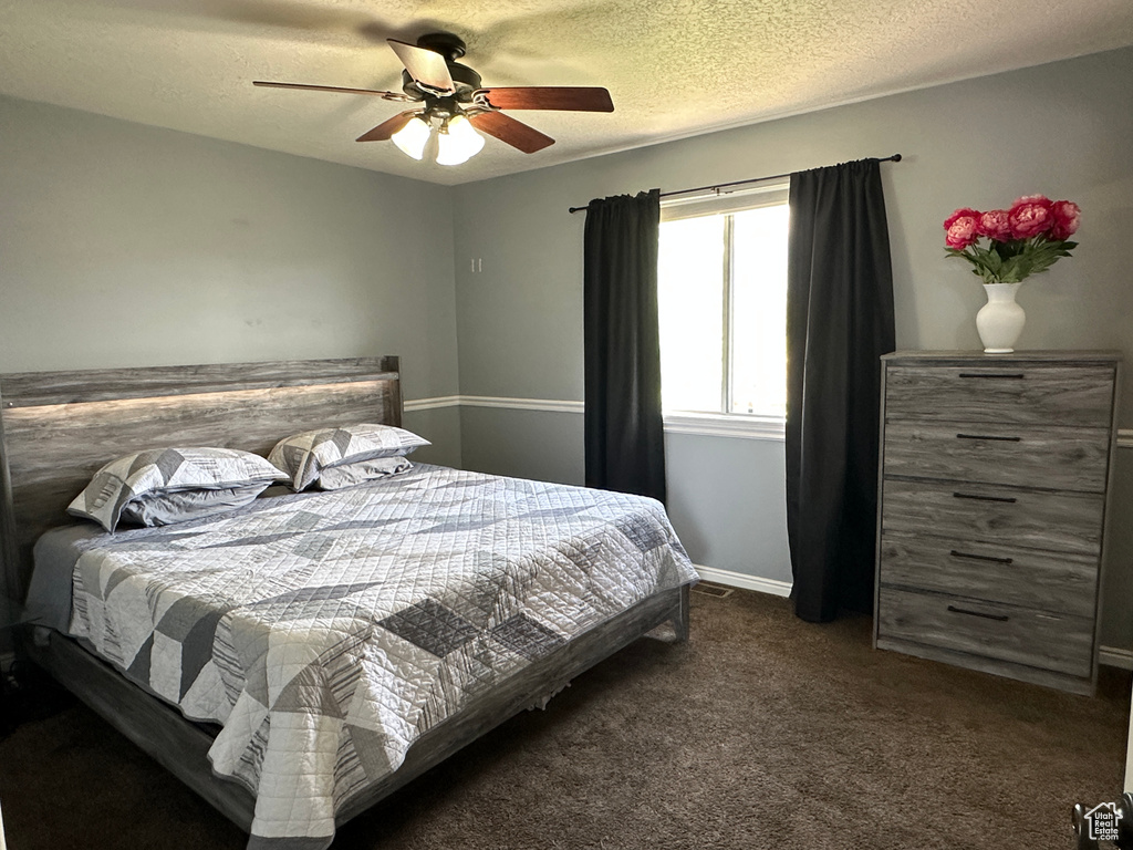 Carpeted bedroom featuring ceiling fan and a textured ceiling