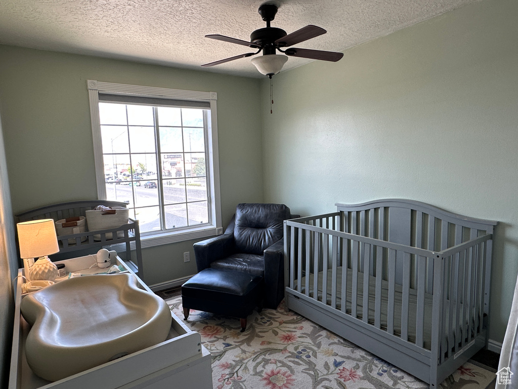 Bedroom with a textured ceiling, multiple windows, and a ceiling fan