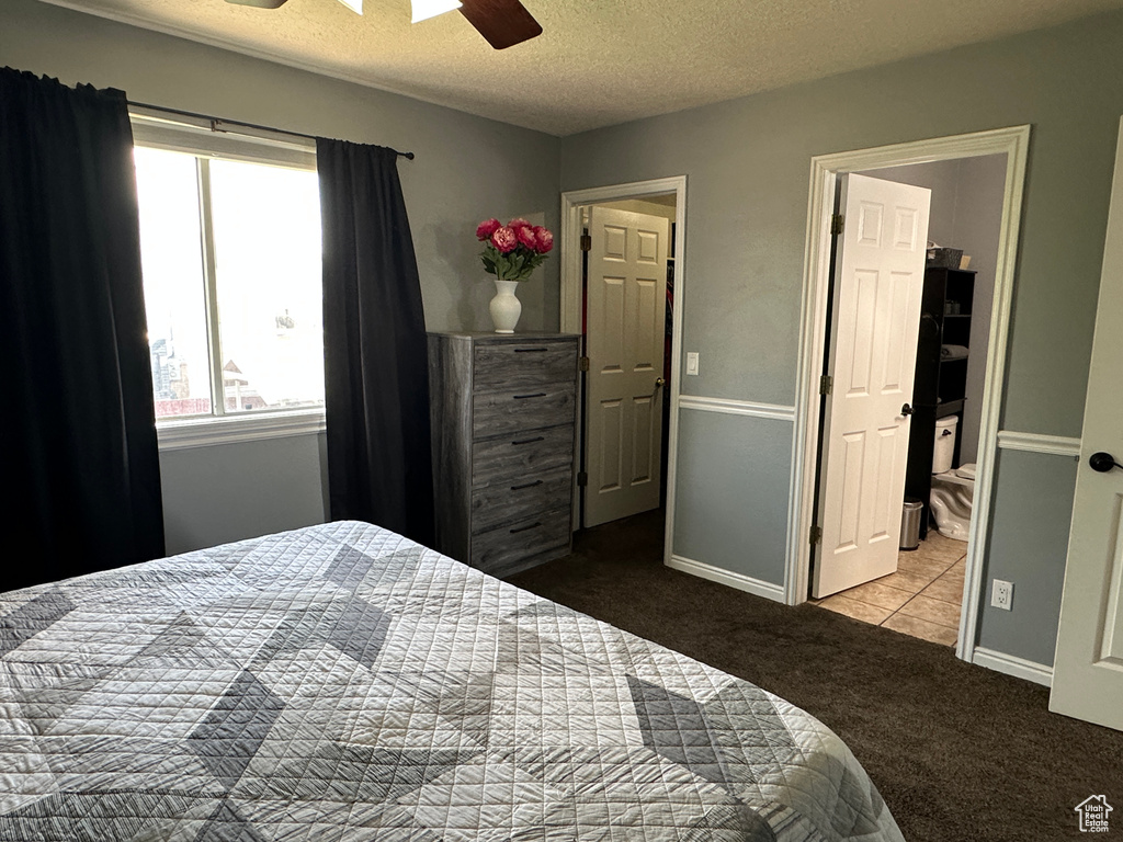 Carpeted bedroom featuring a textured ceiling, ceiling fan, and tile patterned flooring