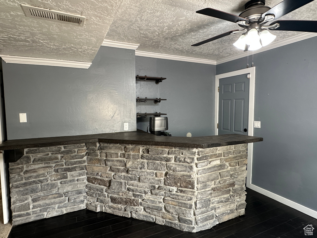 Indoor bar with wood finished floors, ceiling fan, a textured ceiling, and ornamental molding