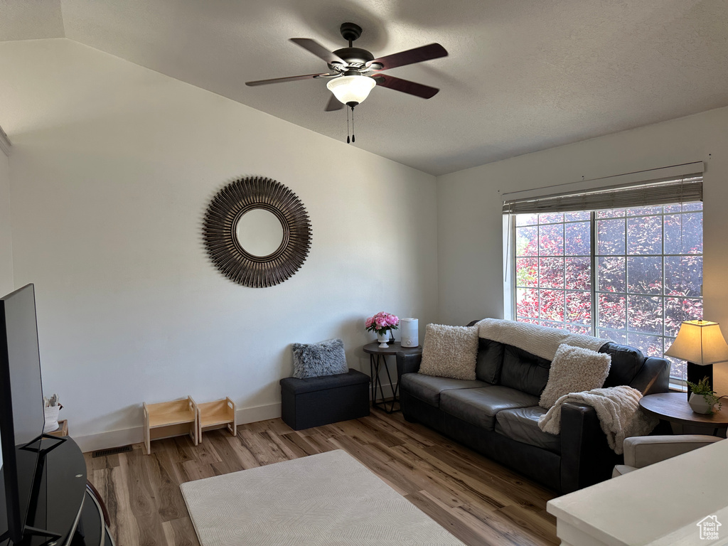 Living area featuring vaulted ceiling, wood finished floors, and ceiling fan