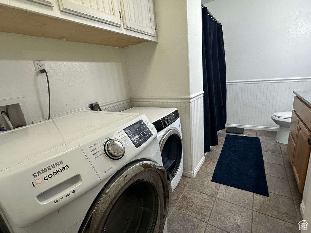 Washroom featuring washing machine and dryer, wainscoting, and light tile patterned flooring