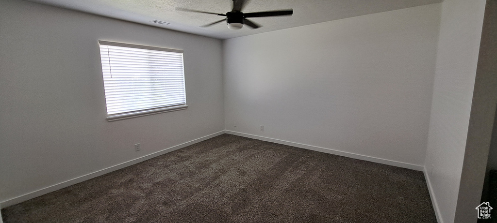 Spare room with ceiling fan and dark carpet