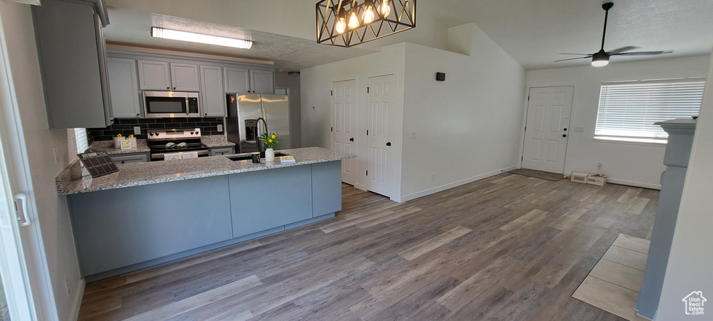 Kitchen with appliances with stainless steel finishes, ceiling fan, decorative backsplash, a peninsula, and gray cabinets
