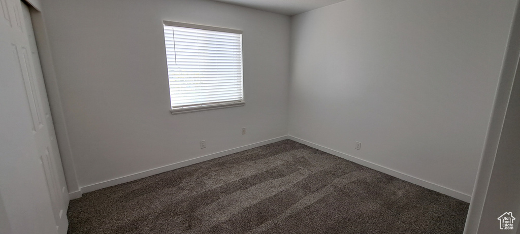 Unfurnished room with dark carpet and baseboards