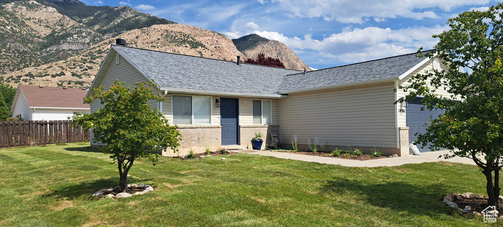 Ranch-style house with a garage, a mountain view, roof with shingles, and brick siding