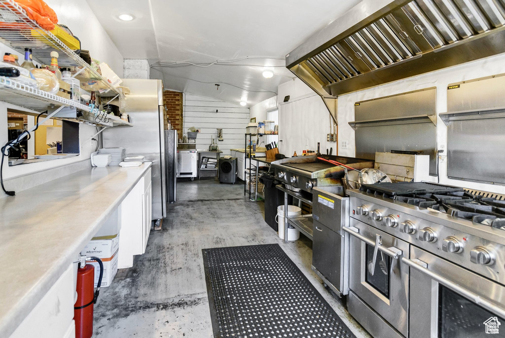 Kitchen featuring stainless steel appliances, concrete flooring, white cabinetry, and light countertops
