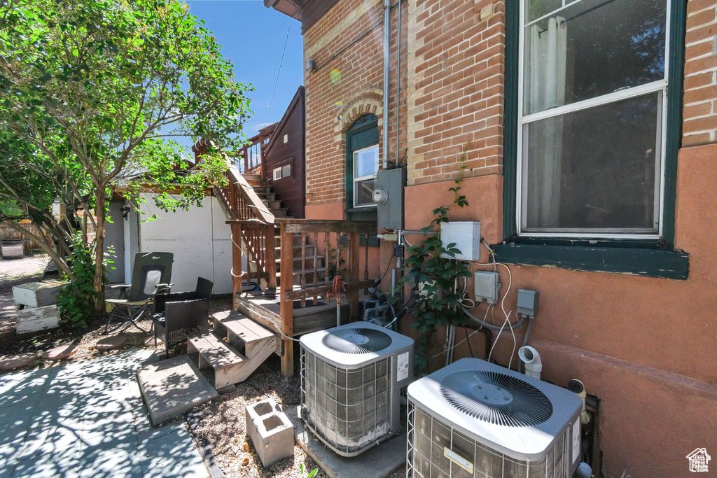 View of property exterior with stairs, brick siding, and a patio area