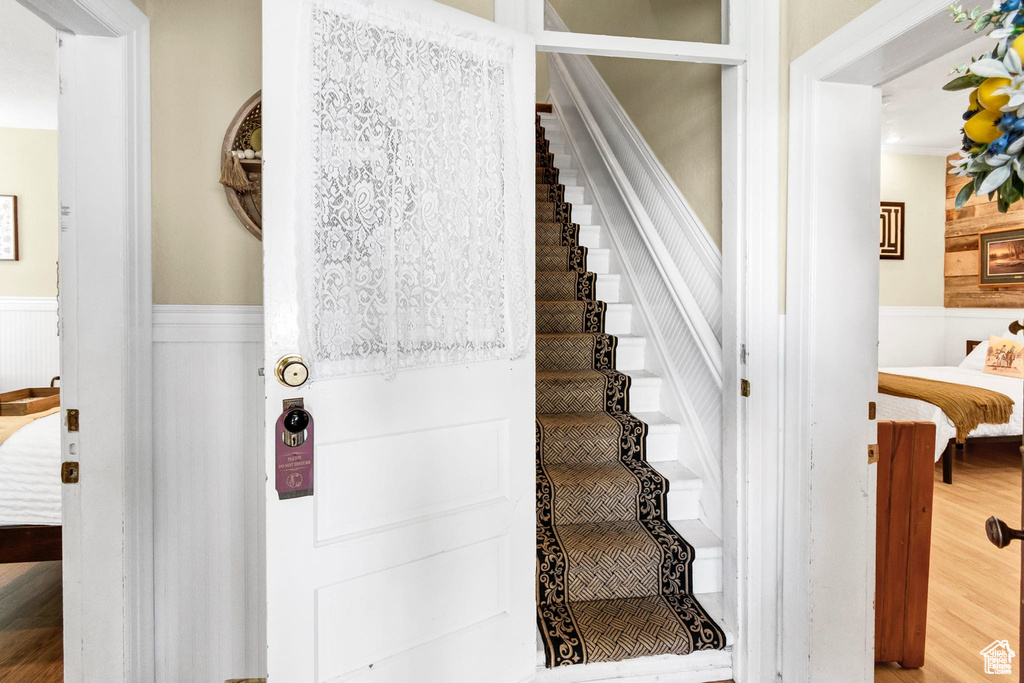 Staircase featuring wainscoting and wood finished floors