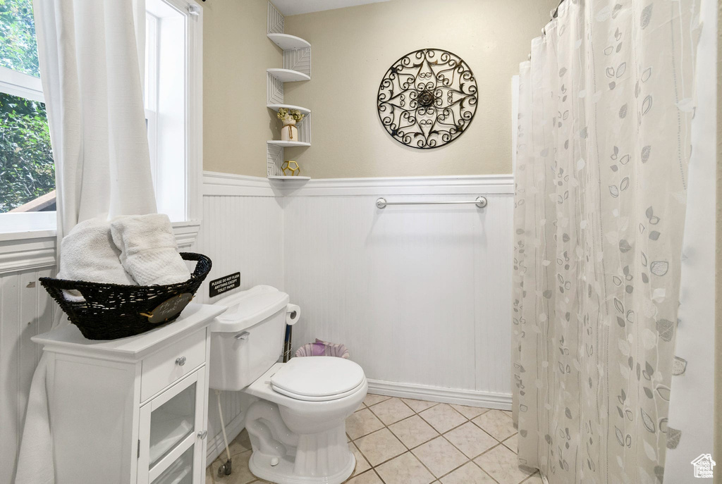 Full bath featuring a wainscoted wall, tile patterned flooring, and a shower with curtain