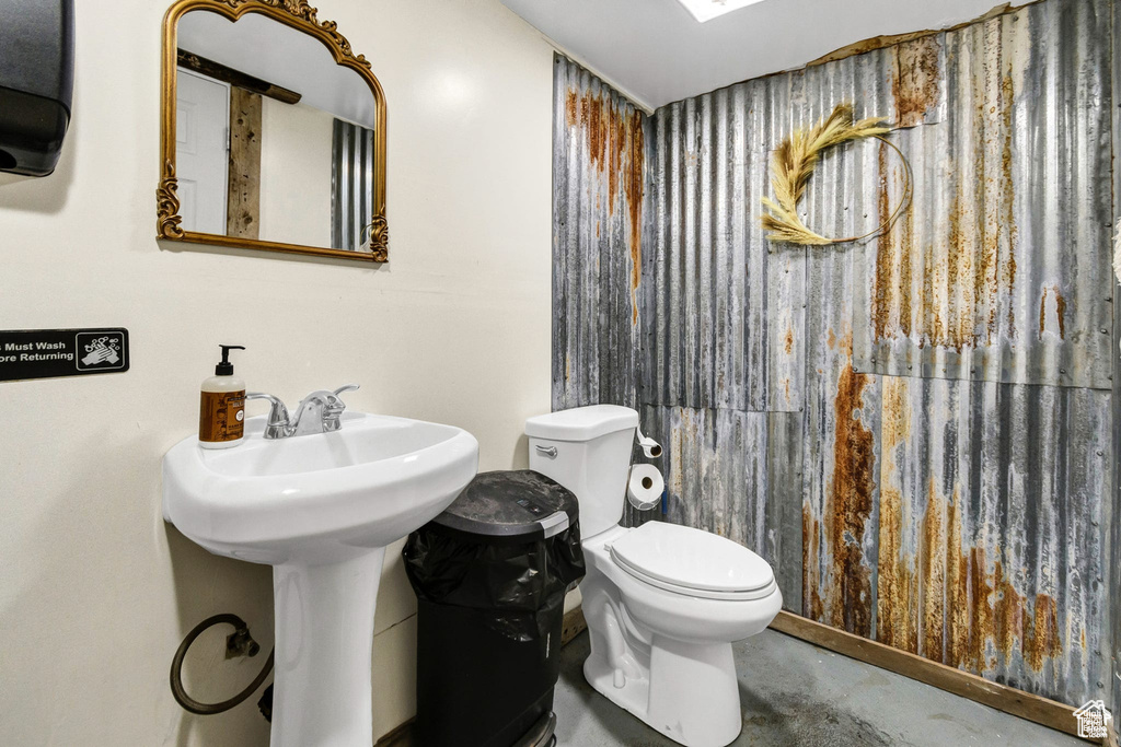 Bathroom featuring concrete flooring and toilet
