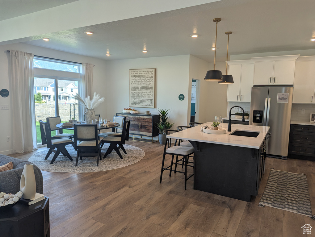 Kitchen featuring stainless steel fridge with ice dispenser, dark wood-style flooring, a breakfast bar area, light countertops, and recessed lighting